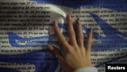 FILE - A girl puts her hand on a list of names of Israelis killed since the October 7 attack by Palestinian Islamist group Hamas, during a 24-hour protest, that calls for the release of Israeli hostages in Gaza in Tel Aviv, Israel, January 13, 2024.