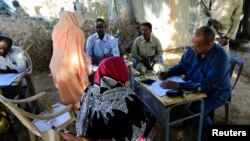 FILE - Yasir Ahmed Mohamed, seated at right, special prosecutor for crimes in Darfur, and his team talk to women during an investigation into allegations of mass rape in Thabit, Nov. 20, 2014.