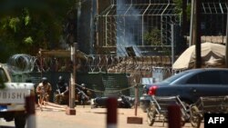 Des militaires se protègent alors que de la fumée s’échappe de l'Institut français de Ouagadougou, Burkina Faso, le 2 mars 2018 