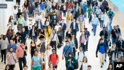 FILE - In this June 21, 2019, file photo commuters walk through a corridor in the World Trade Center Transportation Hub in New York. 