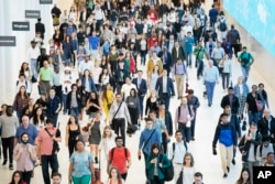 FILE - In this June 21, 2019, file photo commuters walk through a corridor in the World Trade Center Transportation Hub in New York. Millennial workers are more likely than older generations to…