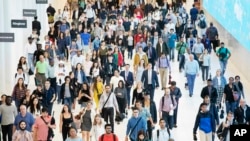 FILE - In this June 21, 2019, file photo commuters walk through a corridor in the World Trade Center Transportation Hub in New York. Millennial workers are more likely than older generations to…