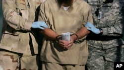 FILE - A shackled detainee is being escorted away from an Administrative Review Board hearing, at Camp Delta detention center at the Guantanamo Bay U.S. Naval Base in Cuba, Dec. 6, 2006.