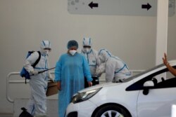 FILE - Health care workers help a woman as she is discharged from the El Salvador Hospital after surviving the coronavirus disease (COVID-19), in San Salvador, El Salvador, Jan. 19, 2021.