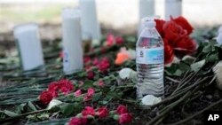 Una botella de agua, flores, velas y peluches fueron depositados en el lugar donde las autoridades descubrieron el sábado un tráiler lleno de inmigrantes en San Antonio, Texas, el lunes, 24 de julio de 2017. (AP Foto / Eric Gay)