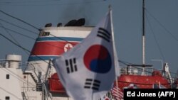 Pengunjuk rasa Korea Selatan mengibarkan bendera di sebuah feri yang membawa rombongan seni Korea Utara untuk Olimpiade Musim Dingin Pyeongchang 2018 di Donghae pada 6 Februari 2018. (Foto: AFP/Ed Jones)