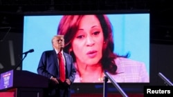 ARCHIVO - El candidato presidencial republicano y expresidente de EEUU, Donald Trump, observa mientras aparece el rostro de la candidata presidencial demócrata y vicepresidenta, Kamala Harris, durante un mitin en Huntington Place en Detroit, EEUU, el 18 de octubre de 2024