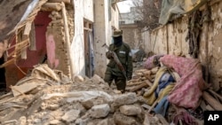 FILE - A Taliban fighter checks remnants of an alleged Islamic State group hideout which the Taliban said it destroyed as part of operations targeting IS militants, in Kabul, Afghanistan, Feb. 14, 2023.