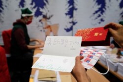 A postal worker shows an envelope from Jim of Taiwan, who sent a face mask inside the letter he sent and wrote 'I (heart) U,' in Libourne, southwest France, Nov. 23, 2020.