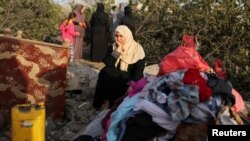 A Palestinian woman reacts as she sits at the remains of a house destroyed in an Israeli air strike in the southern Gaza Strip, Nov. 13, 2019. 