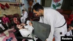 Wasim Stouta, karateka sabuk hitam, pengungsi dari Aleppo, pendiri sekolah dan karate dojo, tengah melatih seorang anak penyandang disabilitas di desa al-Jeineh, Suriah 11 April 2021. (REUTERS/Khalil Ashawi).