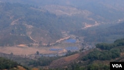 位於中緬邊境大山里的克欽難民營（藍色屋頂）。從中國境內一側拍攝。 （美國之音朱諾拍攝，2015年3月16日）