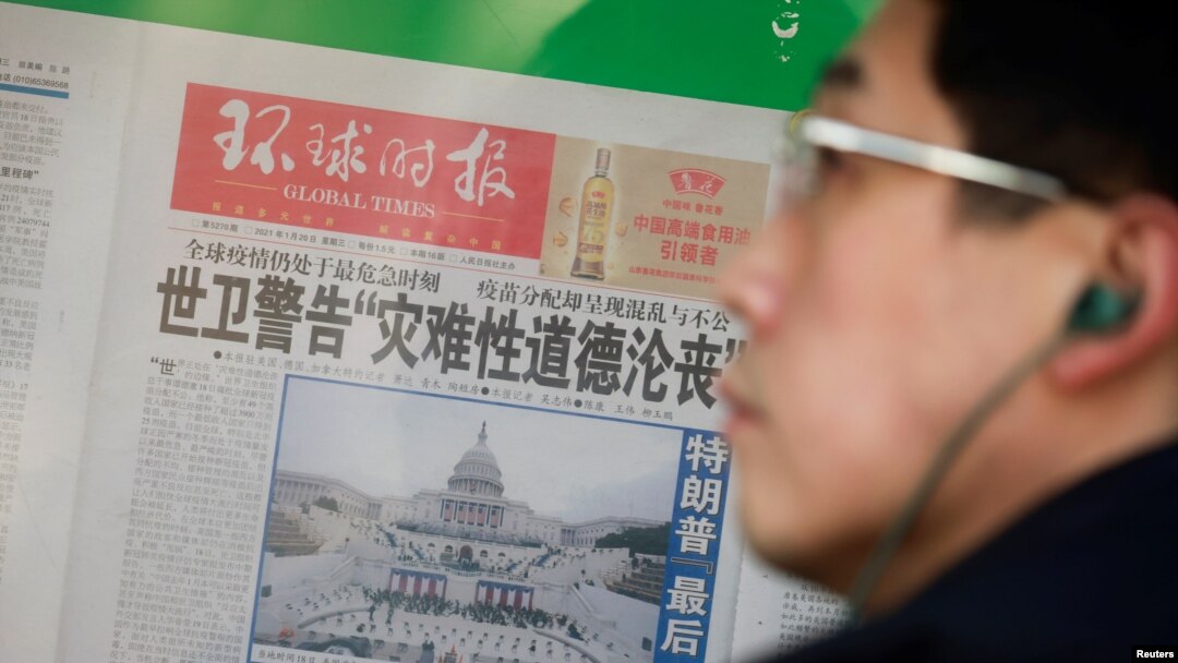 Seorang pria berdiri di depan salinan koran Global Times yang menampilkan foto pelantikan Presiden AS Joe Biden di Beijing, China, 21 Januari 2021.