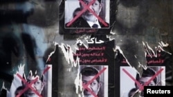 FILE - Torn posters of ousted Egyptian president Mohamed Morsi are seen on a wall at Tahrir Square in Cairo.