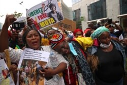 Protestors hold signs and chant slogans during a demonstration against the government of Cameroon and French involvement in government affairs outside an EU summit in Brussels, July 17, 2020.