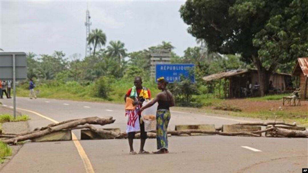 In this photo taken on Tuesday, Aug. 19, 2014, traders speak to one another at a makeshift border control point at one of the largest trading areas catering for people from the Kambia District, in Kambia, Guinea. Since the Ebola virus outbreak the border has been closed with the local population's movement stopped as a attempt to stop the virus from spreading. Kambia district provides an important trade route to or from Guinea's capital Conakry, and to or from Sierra Leone's capital Freetown. (AP Photo/ Youssouf Bah)