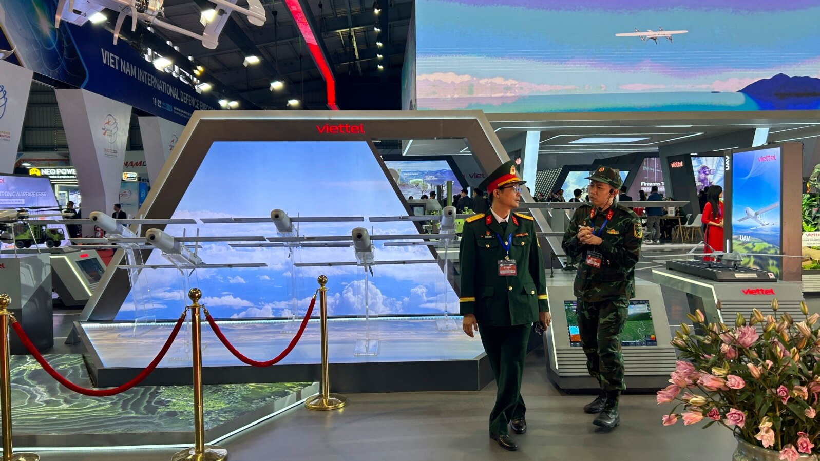 Two men in Vietnamese military uniforms walk next to a stall by Vietnamese state-owned firm Viettel at the Vietnam International Defense Expo, in Hanoi, Dec.19, 2024. 