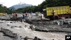 Sand miners collecting sand flowed from the eruption of Mount Merapi, as seen in the background.