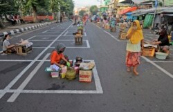 Para pedagang merapkan jaga jarak dengan menempati posisi yang telah ditandai sebagai upaya untuk menekan penyebaran Covid-19 di pasar tradisional di Surabaya, Jawa Timur, 3 Juni 2020. (AP Photo / Trisnadi)