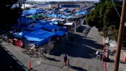 Migrantes caminan fuera de un campamento que bloquea la entrada a un paso de peatones hacia Estados Unidos el 8 de noviembre de 2021, en Tijuana, México.