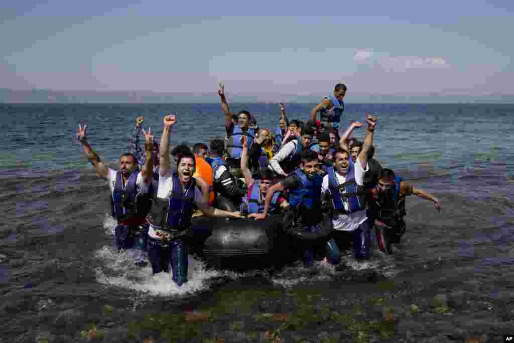 Refugees and migrants react as they arrive on a dinghy from Turkey to Lesbos island, Greece. The flow of migrants across the Mediterranean from Syria, Iraq, Aghanistan and Eritrea has hit record proportions this year.