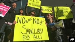 FILE - In this April 2017 photo, protesters hold signs outside a courthouse where a federal judge was to hear arguments in a lawsuit challenging President Donald Trump's executive order to withhold funding from communities that limit cooperation with immigration authorities in San Francisco.