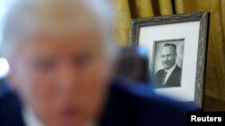 FILE - A photo of U.S. President Donald Trump's late father Fred Trump is seen behind him as he gives an interview in the Oval Office at the White House in Washington, Feb. 23, 2017. 