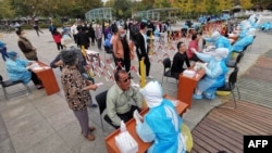 Petugas medis melangsungkan tes swab Covid-19 massal di Qingdao, di provinsi Shandong timur China, 13 Oktober 2020. (Foto oleh STR / AFP)