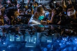 FILE - Hong Kong pro-democracy media mogul Jimmy Lai pushes through a media pack to get to a waiting vehicle after being released on bail from the Mong Kok police station in Hong Kong, Aug. 12, 2020.