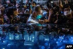 FILE - Hong Kong pro-democracy media mogul Jimmy Lai pushes through a media pack to get to a waiting vehicle after being released on bail from the Mong Kok police station in Hong Kong, Aug. 12, 2020.