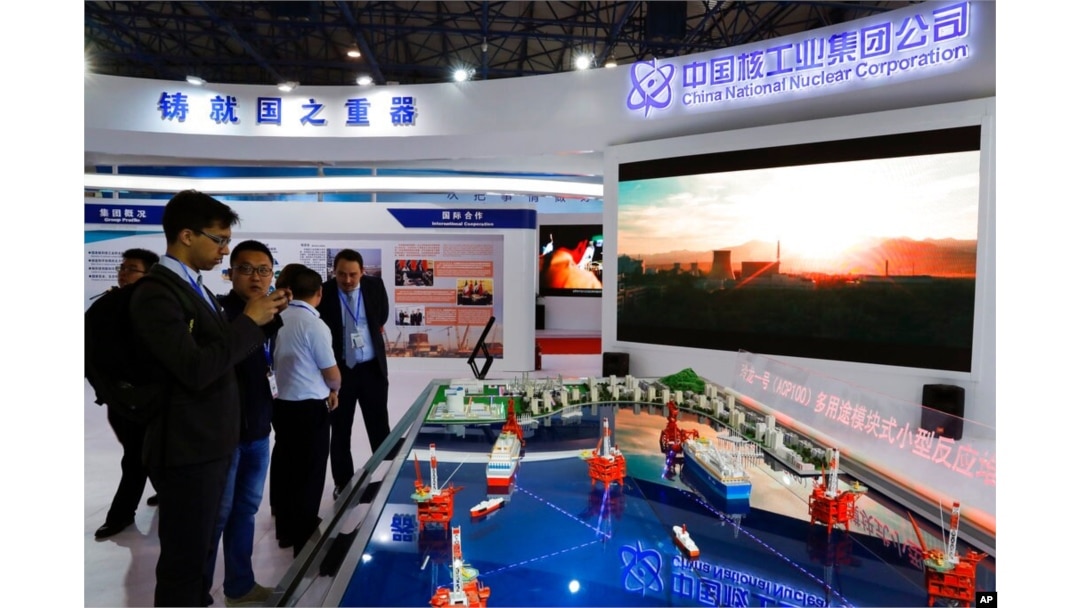 FILE - Staff members from the China National Nuclear Corporation look at models of oil tanker-shaped floating nuclear reactors and oil rigs showcased at the display booth of China's state-owned CNNC, in Beijing, April 27, 2017.