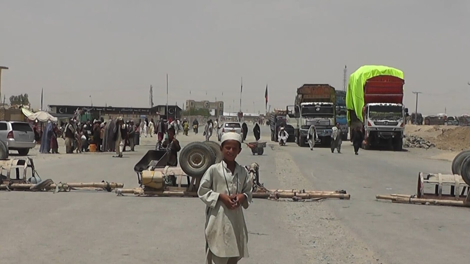 FILE - A boy stands at the closed Chaman border crossing between Pakistan and Afghanistan with trucks seen stranded in the background.