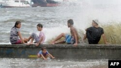 Residents along Manila Bay play in the waves created by nearby Typhoon Noul as it approaches the northern Philippines, May 10, 2015. 