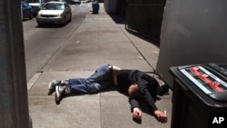 FILE - In this April 26, 2018, file photo, a man lies on the sidewalk beside a recyclable container in San Francisco, California. A record 621 people died of drug overdoses in San Francisco so far this year, a number far higher than the 173 deaths from CO