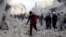 People run on debris at a site hit by what activists said was an airstrike by forces loyal to Syria's President Bashar al-Assad in Aleppo, December 18, 2013.