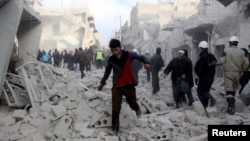 People run on debris at a site hit by what activists said was an airstrike by forces loyal to Syria's President Bashar al-Assad in Aleppo, December 18, 2013.