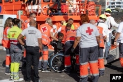 FILE - Anggota Palang Merah Spanyol membantu seorang migran turun setelah perahu 'cayuco' yang membawa 58 migran, termasuk 3 perempuan dan 4 anak-anak, salah satunya buta, tiba di pelabuhan La Restinga di Pulau Canary, El Hierro, 18 September 2024. (Antonio SEMPERE / AFP)