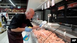 An employee disinfects the glass cover of a butcher counter to prevent the spread of the novel coronavirus in a food store in Budapest, Hungary, Wednesday, March 11, 2020.
