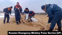 In this photo taken from video released by Russian Emergency Ministry Press Service on Jan. 4, 2025, workers clean fuel oil that spilled out of two tankers more than two weeks ago in the Kerch Strait in Russia's Krasnodar region. (Russian Emergency Ministry Press Service via AP)