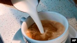 FILE - A barista pours steamed milk into a cup of coffee at a cafe in Los Angeles, Sept. 22, 2017. 