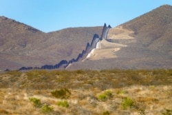 FILE - Newly erected border wall separating Mexico, left, and the United States, cuts through through the Sonoran Desert just west of the San Bernardino National Wildlife Refuge, Dec. 9, 2020, in Douglas, Ariz.