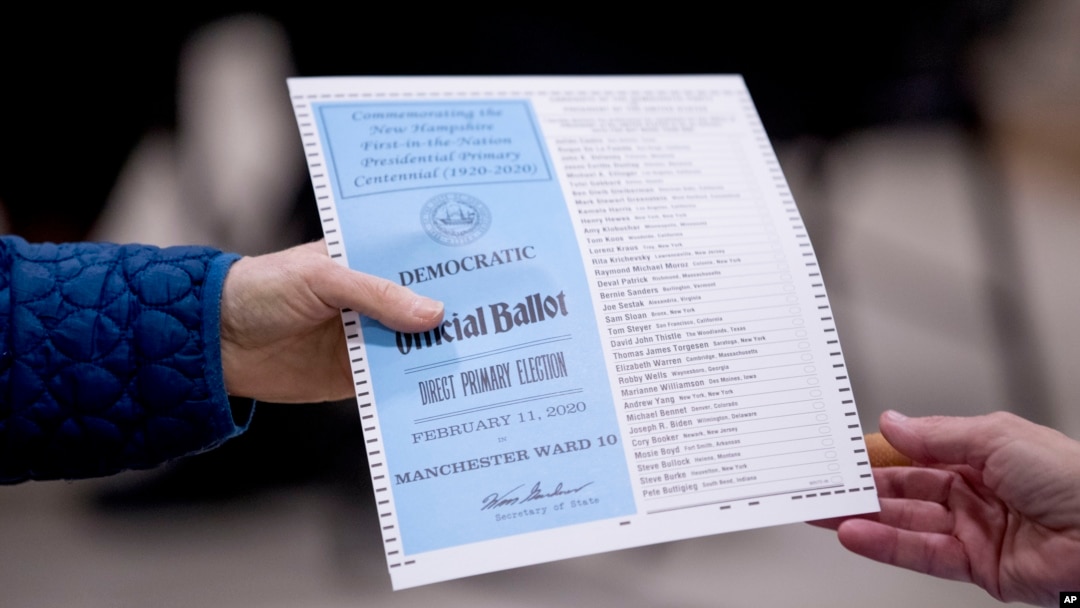 A woman takes a Democratic ballot to vote in the New Hampshire Primary at Parker-Varney Elementary School, Tuesday, Feb. 11, 2020, in Manchester, N.H. (AP Photo/Andrew Harnik)