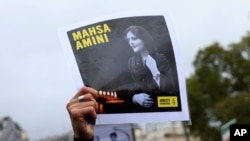 FILE - Seorang pengunjuk rasa di Paris, Prancis, menunjukkan potret Mahsa Amini saat berlangsungnya aksi solidaritas untuk mendukung pengunjuk rasa Iran atas kematian seorang wanita muda dalam tahanan polisi, Minggu, 2 Oktober 2022. (AP/Aurelien Morissard)