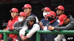 Para pemain SK Wyvern mengenakan masker, menonton pertandingan dari ruang istirahat selama pertandingan pembukaan melawan Hanwha Eagles untuk musim baseball Korea Selatan yang baru di Munhak Baseball Stadium di Incheon pada 5 Mei 2020.