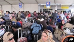 Passengers wait under large tent set-up in the parking lot outside Cairo's International airport as Egyptians and foreigners prepare to leave Egypt, February 01, 2011