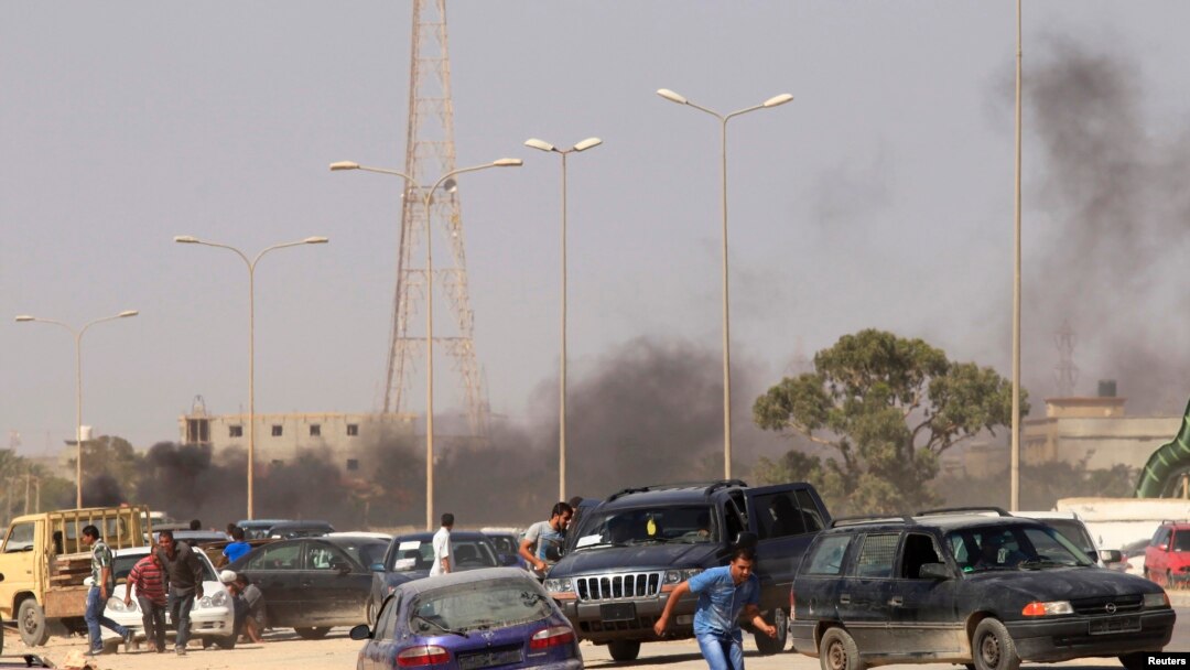 Abari mu myiyerekano bariko bahunga inyuma y'igitero ku barwanyi muri Libya mu gisagara ca Benghazi kw'italiki umunani z'ukwezi kwa gatandatu mu mwaka w'2013.