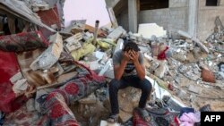 Un joven palestino reacciona sentado sobre los escombros de una casa destruida tras un ataque militar israelí contra el campo de refugiados de Rafah, en el sur de la Franja de Gaza, el 15 de octubre de 2023, en medio de las batallas en curso entre Israel y los palestinos.