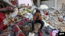 Seorang pemuda Palestina saat duduk di reruntuhan rumah yang hancur menyusul serangan militer Israel di kamp pengungsi Rafah, di selatan Jalur Gaza pada 15 Oktober 2023. (Foto: AFP)