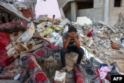 A Palestinian youth reacts as he sits on the rubble of a destroyed home following an Israeli military strike on the Rafah refugee camp, in the south of Gaza Strip, Oct. 15, 2023, amid battles between Israel and the Palestinian Islamist group Hamas.