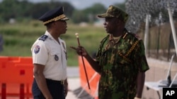 FILE - The spokesperson of the Multinational Security Support Mission for Haiti, General Godfrey Otunge, right, speaks with Haitian National Police general director Rameau Normil, left, in Port-au-Prince, Haiti, Sept. 5, 2024. (Roberto Schmidt/Pool photo via AP)